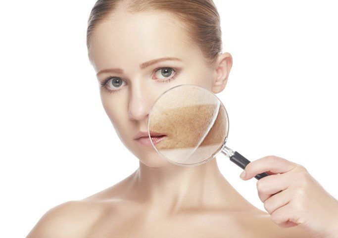 A woman looking through a magnifying glass at her skin