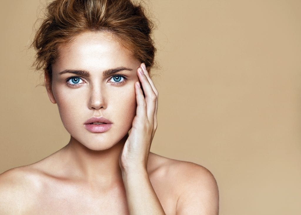 Studio portrait of young beautiful woman with nude make-up. Shooted on beige background