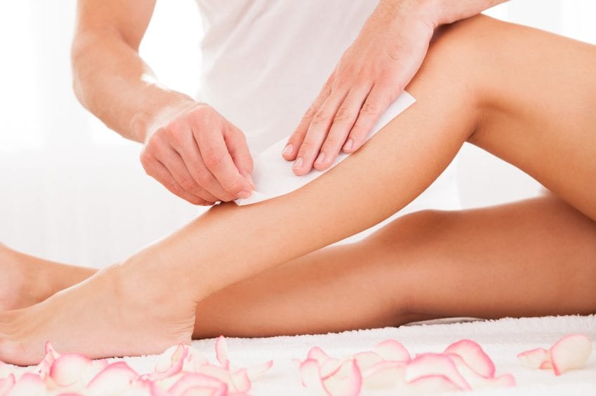 Beautician waxing a woman leg