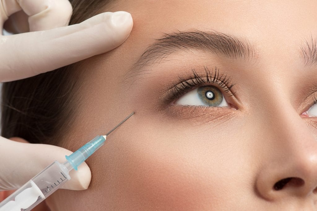 Close up of female eye area getting botox injection by syringe