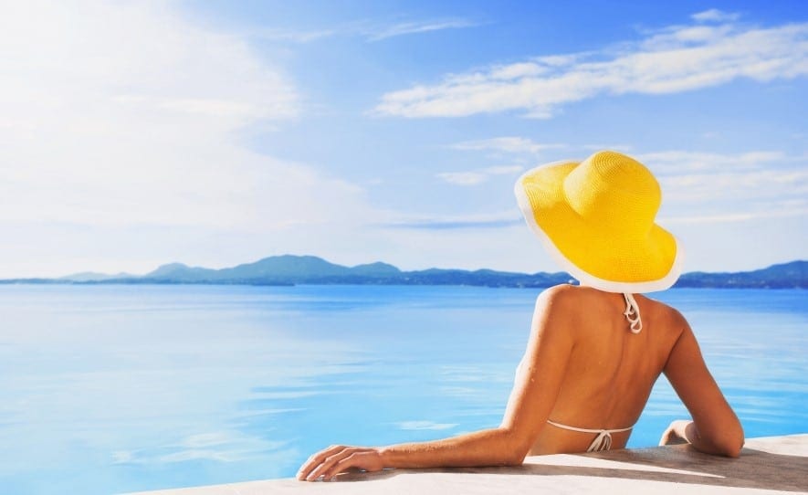 Woman wearing yellow sun hat enjoying the sun in a pool