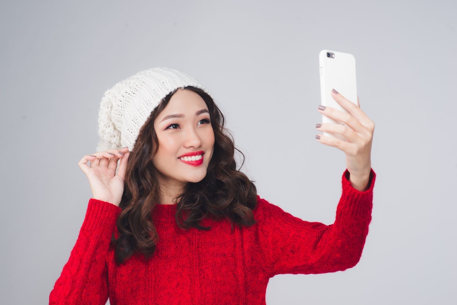 Happy young woman wearing winter clothing taking a selfie photo