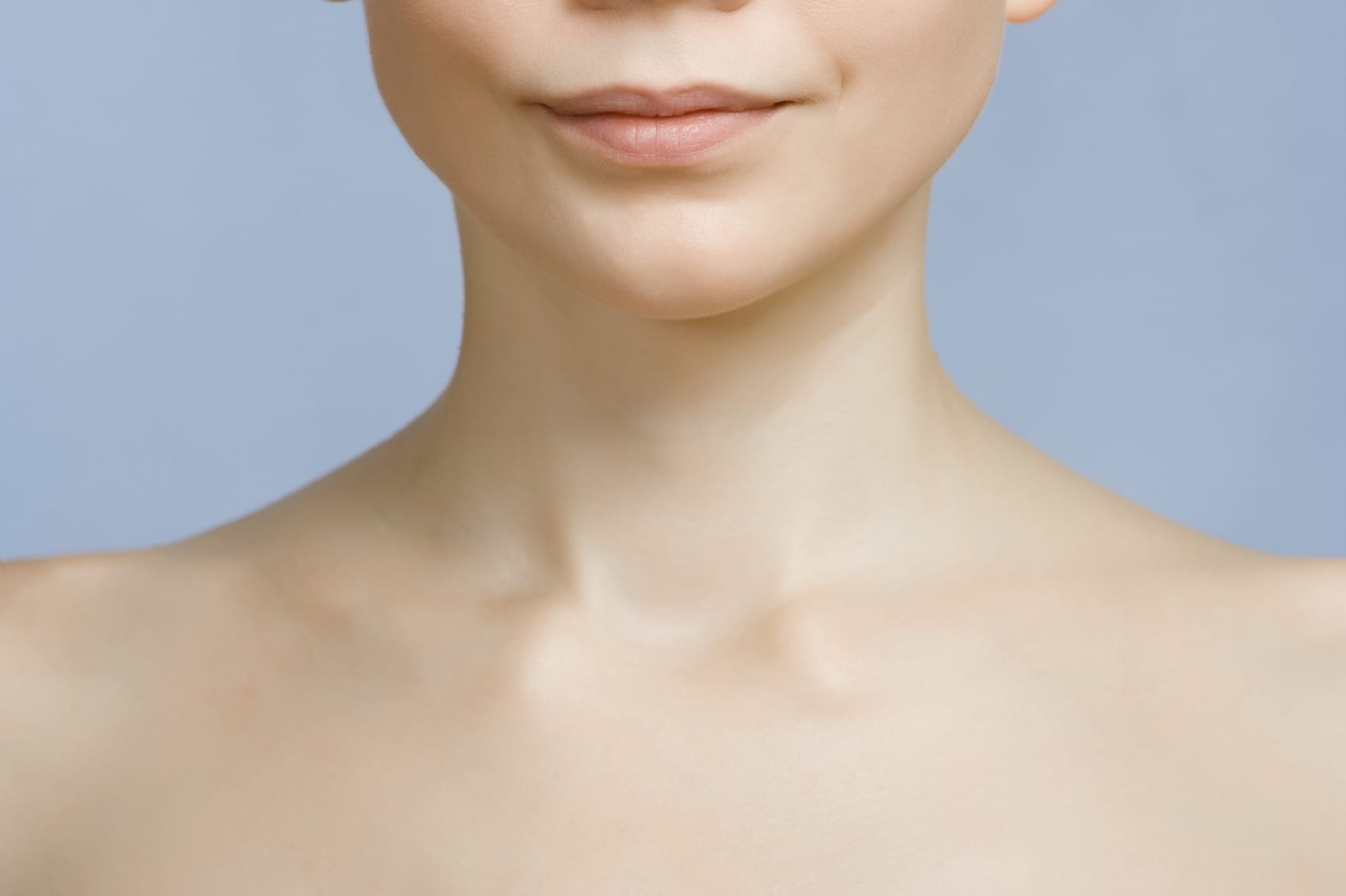 An image of young woman's lips, chin and shoulders. Focus is set at her lips and chin