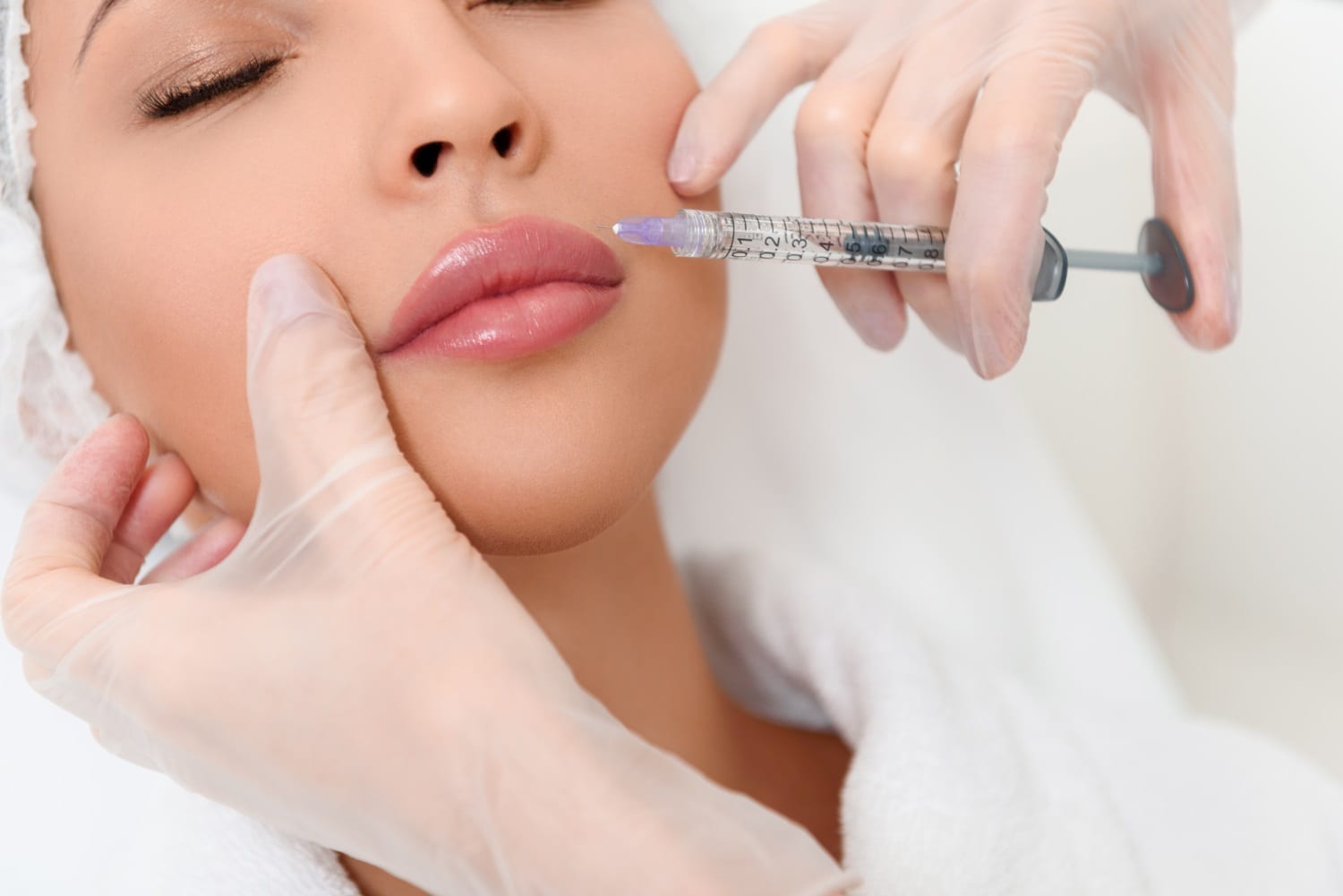 Close up of beautician hands in gloves injecting female lips with botox