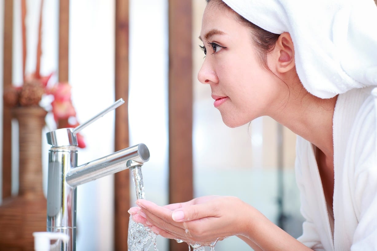 woman cleaning her face with water