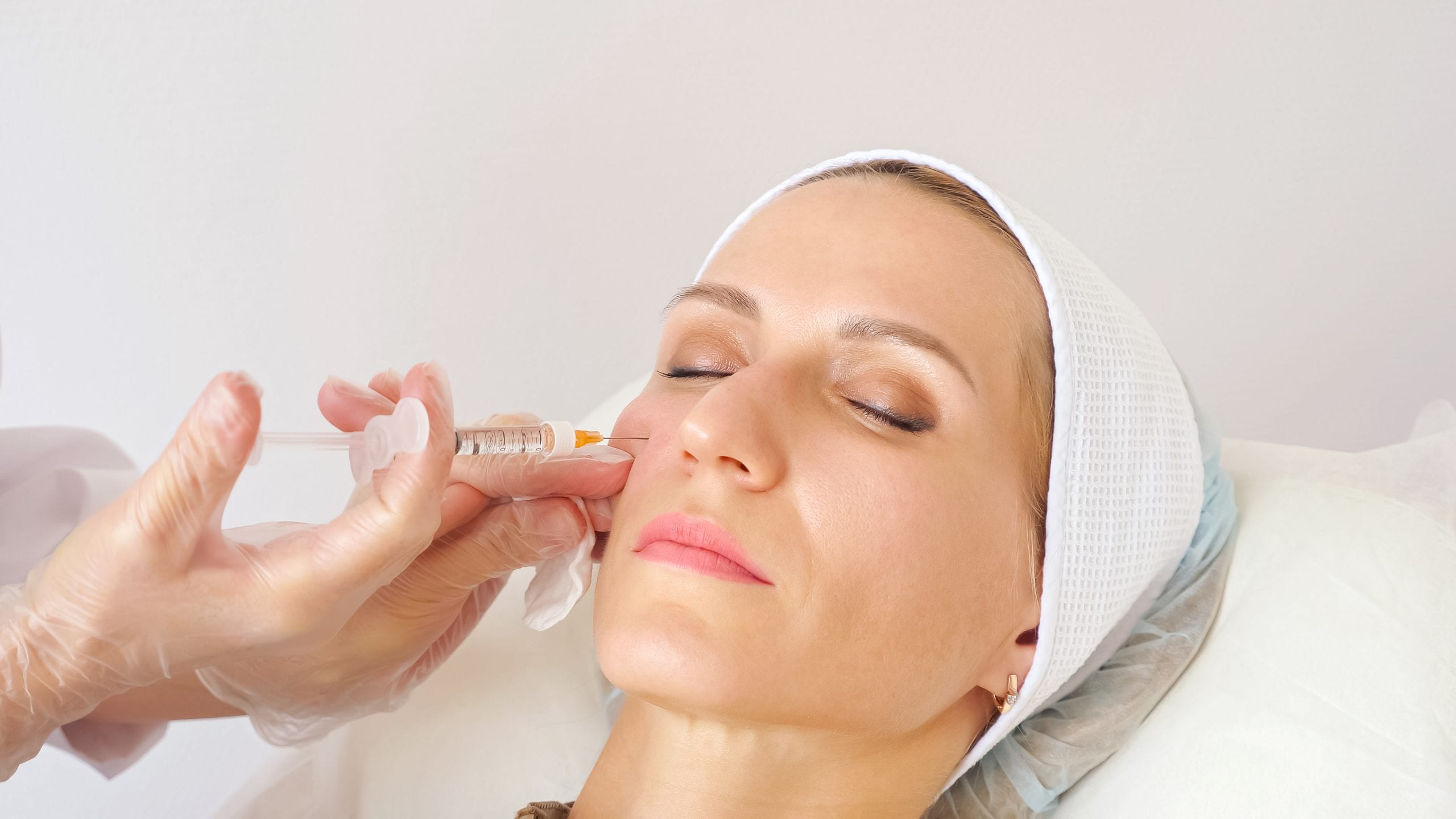 Beautician giving woman cheek injection