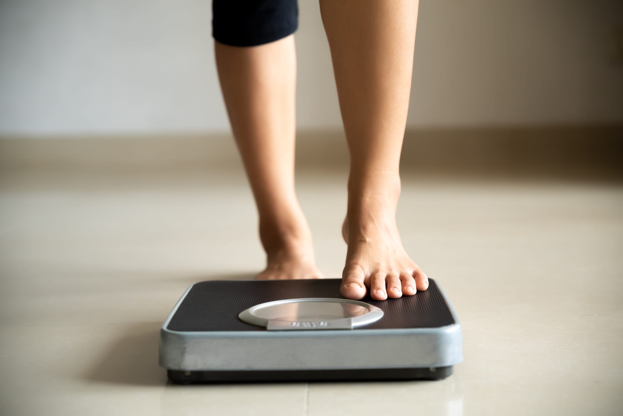 Female leg stepping on weigh scales. 