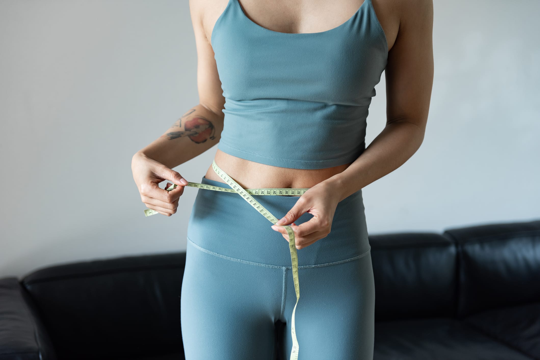 A young woman measures the waist with a ruler