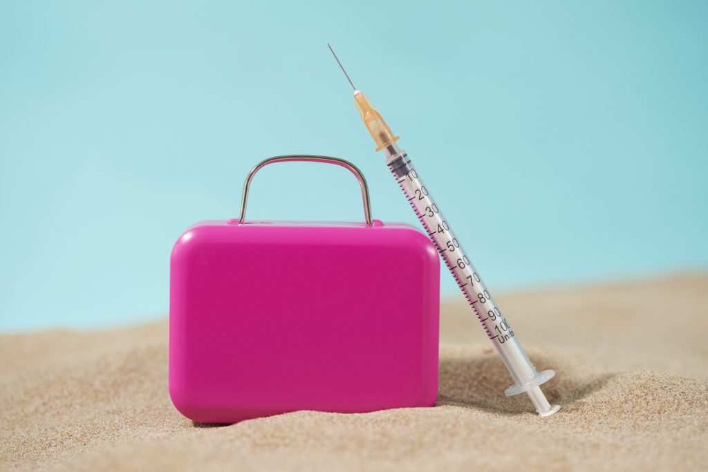Suitcase and dermal fillers on a beach