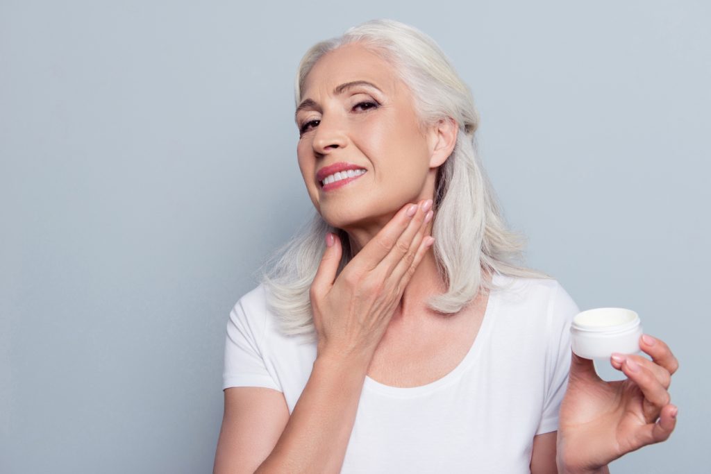 Woman applying lotion to her neck