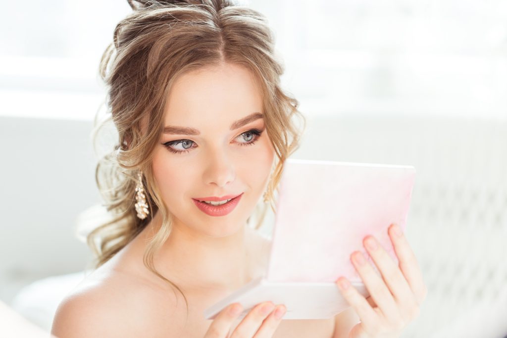 Beautiful bride looking at her make-up in a mirror