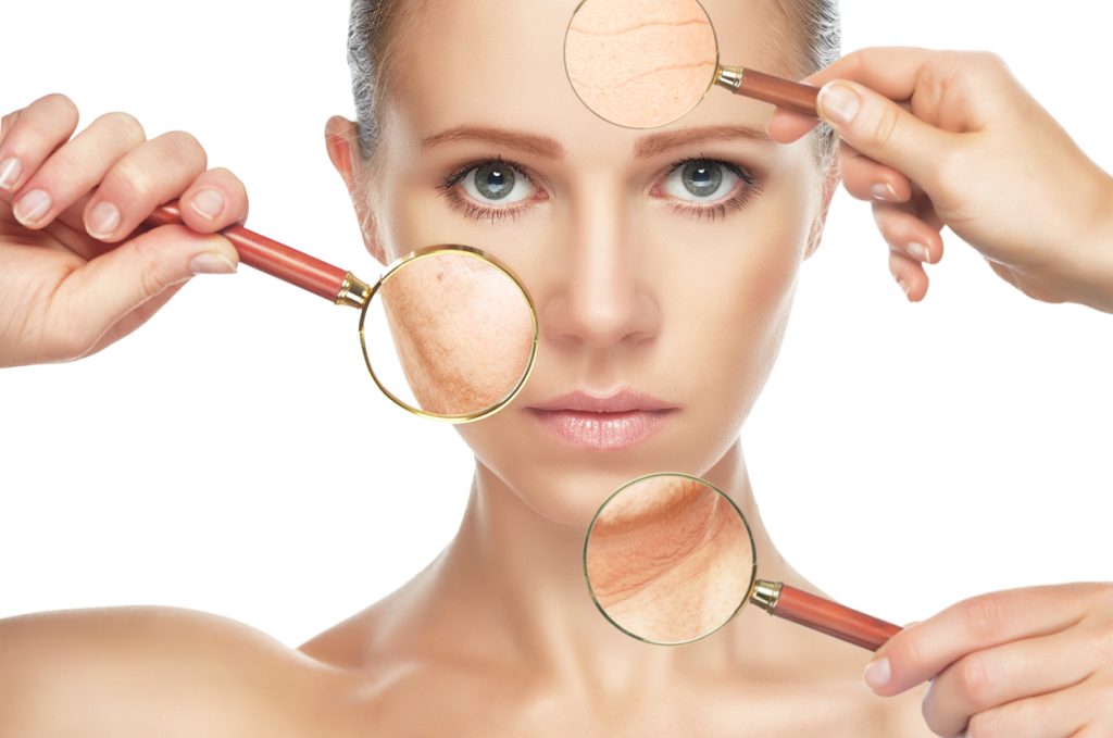 Woman using magnifying glass to look at ageing skin