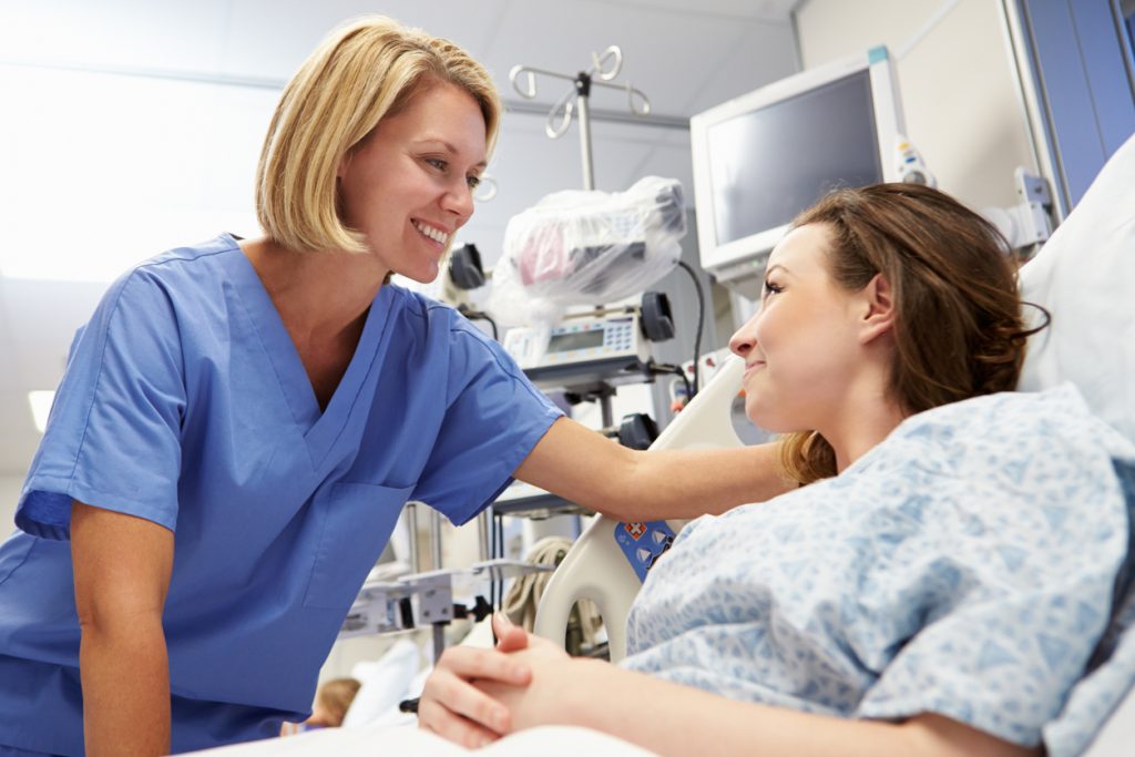 A nurse reassuring a cosmetic surgery patient in a hospital bed