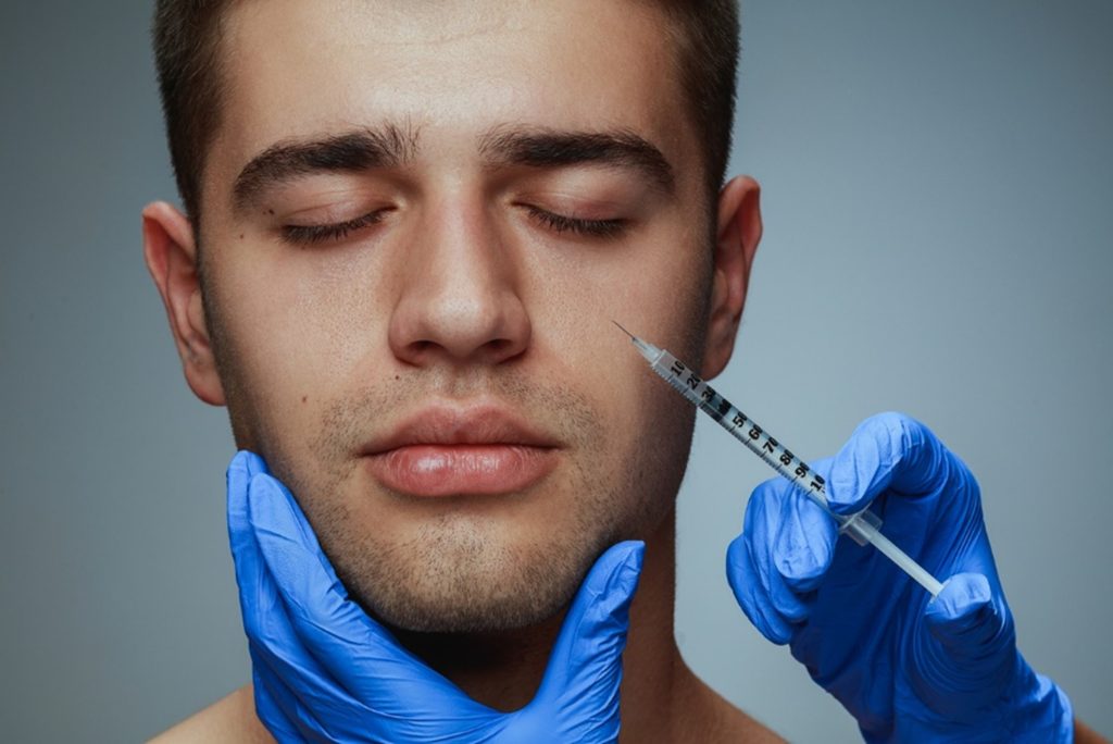 Man receiving dermal filler injections in his cheek