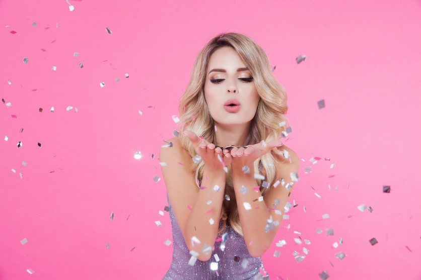 Woman celebrating blowing glittering c