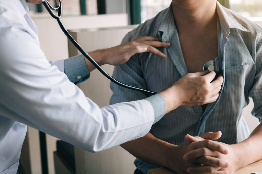 A doctor checking an overweight patient's heart