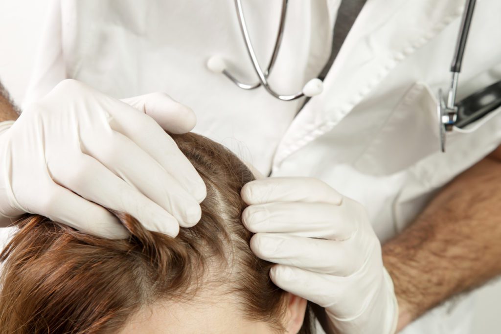 Aesthetic nurse looking at a woman's balding head