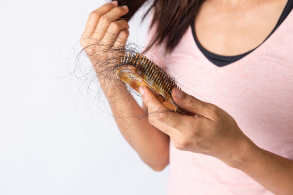Woman suffering from hair loss holding hairbrush with hair fallen out