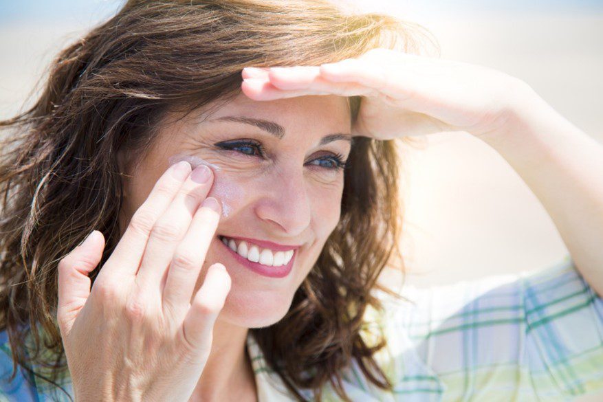 Woman smiling and shielding face from the sun