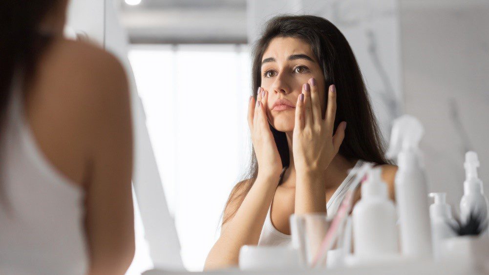Woman looking at her eye bags in the mirror