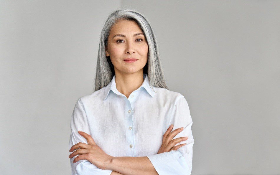 Woman in her 50s folding arms with grey hair