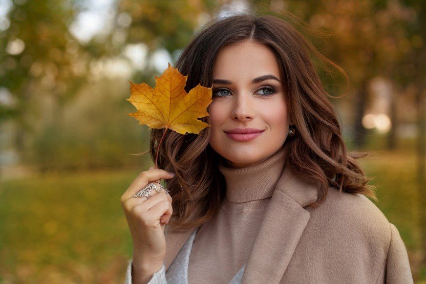 beautiful woman smiling holding a autumnal leaf
