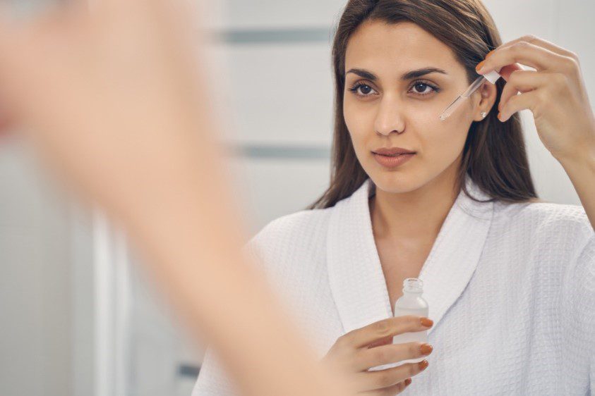 woman putting serum on face