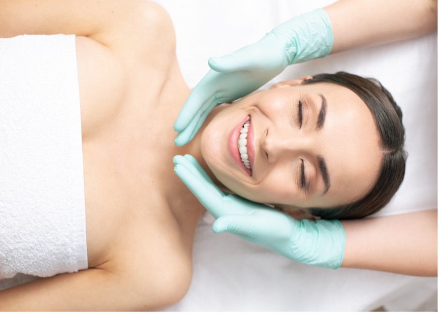 A person lying down with her eyes closed and hands in gloves